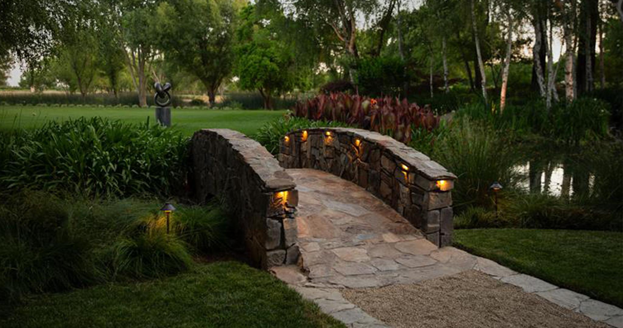 FX Luminaire FX Luminaire highlights this stone bridge with warm path lighting, enhancing texture, safety, and ambiance.